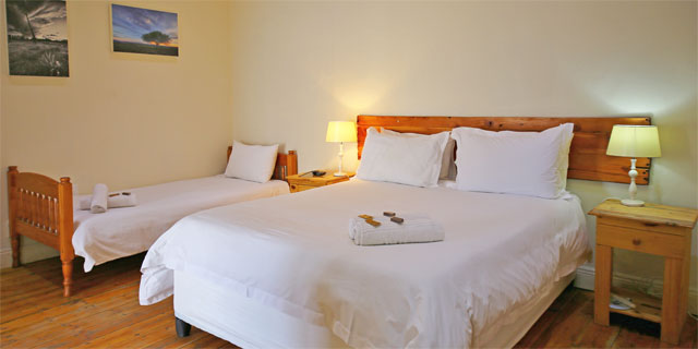 En-suite Room 1 sleeps from 1 to 4 persons in a quality twin/King bed plus 2 single beds. It has a separate enclosed stoep to make it more spacious.